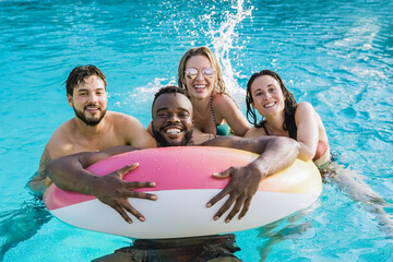Young friends inside swimming pool having fun during summer vacations - Focus on African man