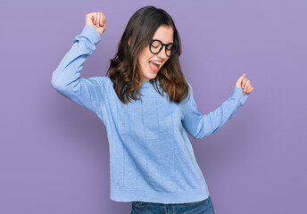 Young beautiful woman wearing casual clothes and glasses dancing happy and cheerful, smiling moving casual and confident listening to music