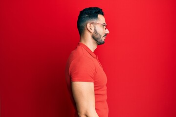 Young hispanic man wearing casual clothes and glasses looking to side, relax profile pose with natural face with confident smile.