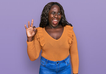 Young african woman wearing casual clothes winking looking at the camera with sexy expression,...
