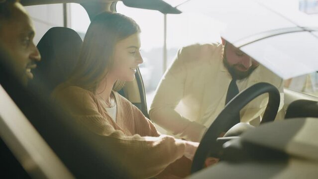 African american man and his caucasian woman visiting dealership center for choosing new transport. Competent dealer in formal wear consulting multi ethnic couple about expensive purchase. Auto salon.