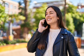 Young woman smiling confident talking on the smartphone at park