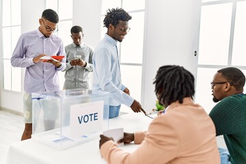 Obraz premium Group of young african american voter people putting vote in ballot standing at electoral center.
