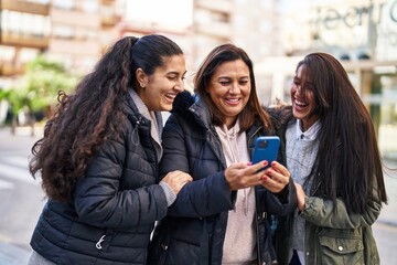 Three woman mother and daughters using smartphone at street