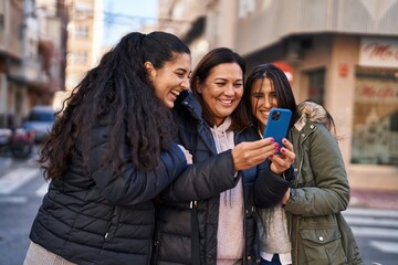 Three woman mother and daughters using smartphone at street