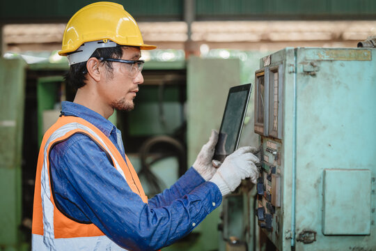 Engineer worker program setup CNC machine in metal industry factory with tablet technology.
