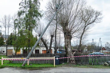 Tilted electric pole with lantern after a storm.