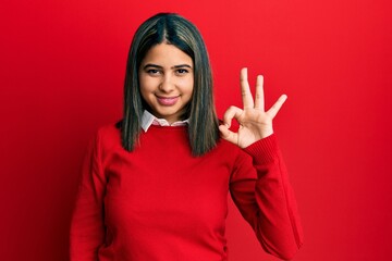 Young latin woman wearing casual clothes smiling positive doing ok sign with hand and fingers. successful expression.