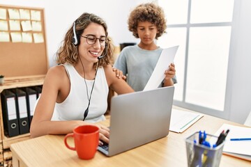 Young business mother working at the office with kid looking positive and happy standing and smiling with a confident smile showing teeth