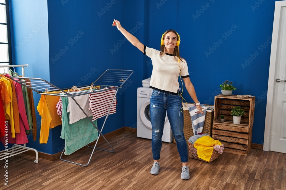 Sticker young blonde woman listening to music and dancing at laundry room