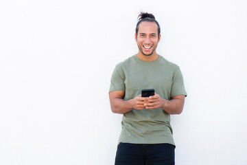 Happy man with pulled up hair bun text messaging using mobile phone over white background