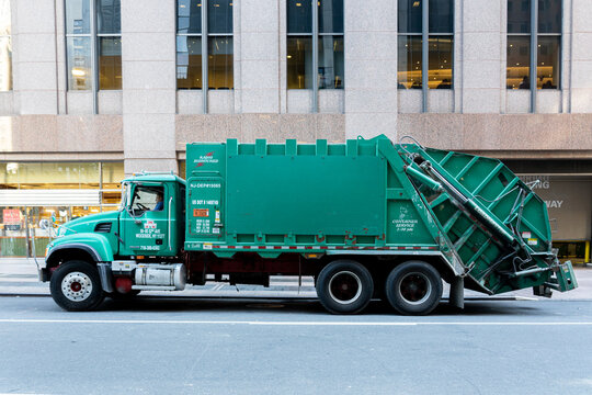 New York, United States - September 20, 2019: A large green trash truck in the streets of Manhattan.