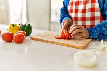 Senior man cutting tomato at kitchen