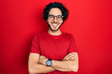 Obraz premium Handsome hispanic man wearing casual t shirt and glasses happy face smiling with crossed arms looking at the camera. positive person.