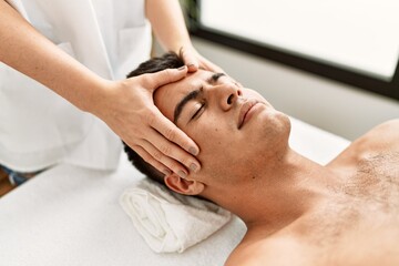 Fototapeta na wymiar Young hispanic man relaxed having facial massage at beauty center
