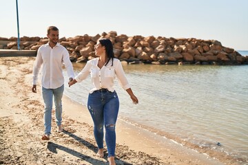 Man and woman couple smiling happy walking at seaside