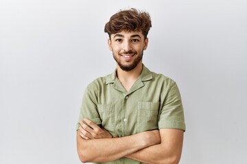Young arab doctor man standing over isolated background happy face smiling with crossed arms looking at the camera. positive person.