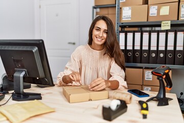 Young hispanic woman smiling confident packing order at storehouse