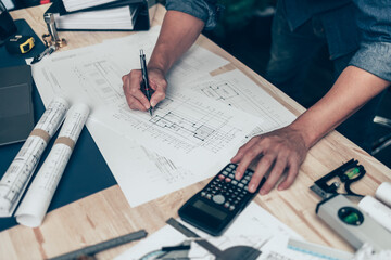 Architect engineer use calculator for calculate drawing design working on blueprint. House planning...