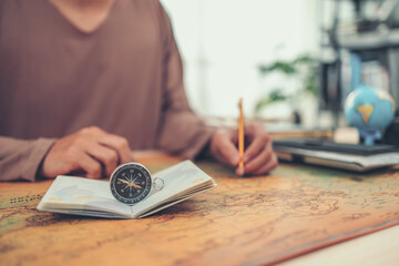 Magnetic compass on passport and man use pen marking location on world map. Travel , Adventure and Discovery concept.