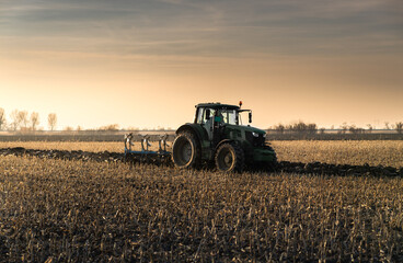 Obraz premium Tractor on the field during sunset.