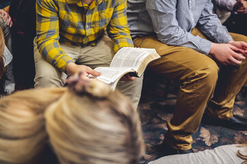 The man in a checkered shirt reading a book in a public place