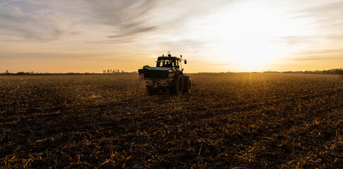 Fototapeta premium Tractor spreading artificial fertilizers in field
