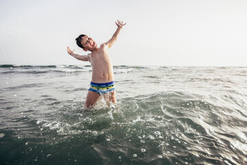 Happy child playing in the sea. Kid having fun outdoors. Summer vacation and healthy lifestyle concept. Selective focus