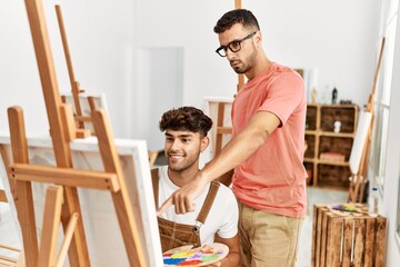 Two hispanic men teacher and student drawing at art studio