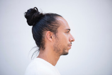 Profile face of man with pulled up hair bun over white background