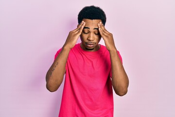 Fototapeta premium Young african american man wearing casua t shirt with hand on head for pain in head because stress. suffering migraine.