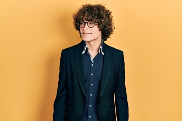 Fototapeta premium Handsome young man wearing business jacket and glasses looking away to side with smile on face, natural expression. laughing confident.
