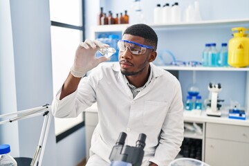 Naklejka na ściany i meble Young african american man wearing scientist uniform holding diamond at laboratory
