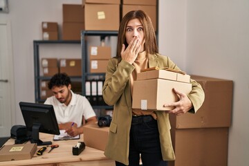 Young two people working at small business ecommerce covering mouth with hand, shocked and afraid for mistake. surprised expression