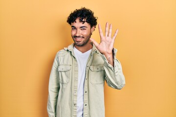 Young hispanic man wearing casual clothes showing and pointing up with fingers number five while smiling confident and happy.