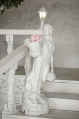 Sculpture of a girl with a basket of flowers standing by the stairs.