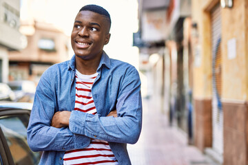Young african american man smiling happy with arms crossed gesture at the city.