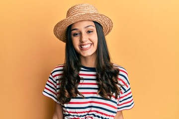 Young hispanic woman wearing summer hat looking positive and happy standing and smiling with a confident smile showing teeth