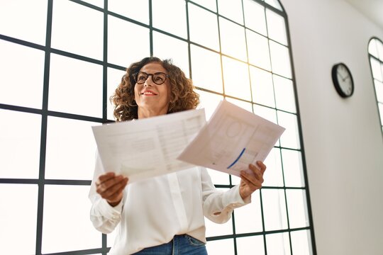 Mature Hispanic Woman Working Looking At Papers At The Office