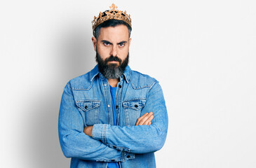 Hispanic man with beard wearing king crown skeptic and nervous, disapproving expression on face with crossed arms. negative person.