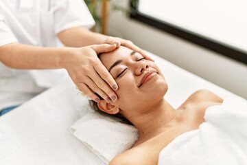 Fototapeta na wymiar Young latin woman relaxed having face massage at beauty center