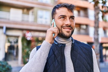 Young hispanic man smiling confident talking on the smartphone at street