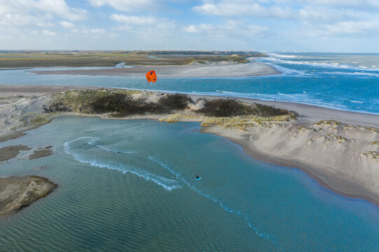 Aerial view of a person doing windsurf among sand dunes in a bay in Retranchement, Netherlands.