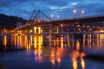 Fototapeta na wymiar Night city landscape. Pedestrian bridge across the Dnieper river, Kyiv, Ukraine