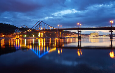 Night city landscape. Pedestrian bridge across the Dnieper river, Kyiv, Ukraine
