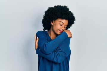 Young african american woman wearing casual clothes hugging oneself happy and positive, smiling...
