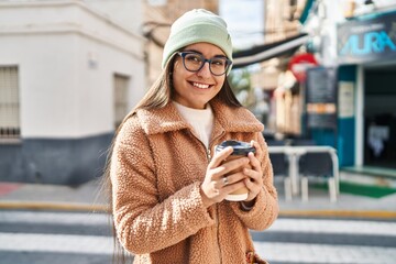 Young hispanic woman smiling confident drinking coffee at street