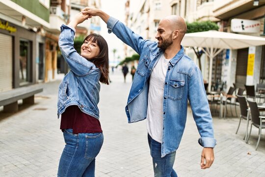 Young hispanic couple smiling happy dancing at the city.