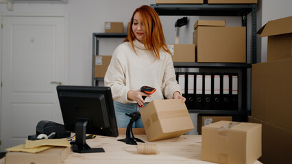 Young redhead woman ecommerce business worker scanning package barcode reader at office