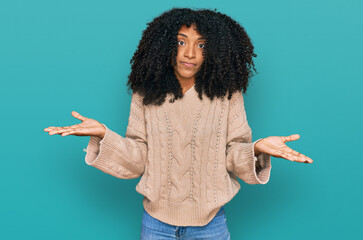 Young african american girl wearing casual clothes clueless and confused expression with arms and...